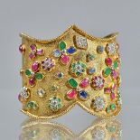 A yellow precious metal and multi gem set cuff bangle,