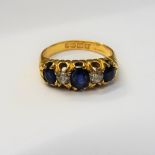 An 18ct gold, sapphire and diamond set five stone ring, mounted with three cushion shaped sapphires,