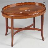 A George III satinwood inlaid mahogany oval serving tray with wavy gallery on later stand,