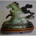 A 20th century Chinese hardstone figure of two horses on a hardwood stand.