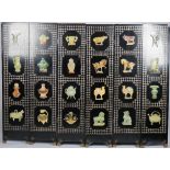 A mid-20th century Eastern black lacquer six fold screen, relief decorated with soapstone vessels,