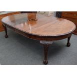 An early 20th century mahogany extending dining table on claw and ball feet, with two extra leaves,