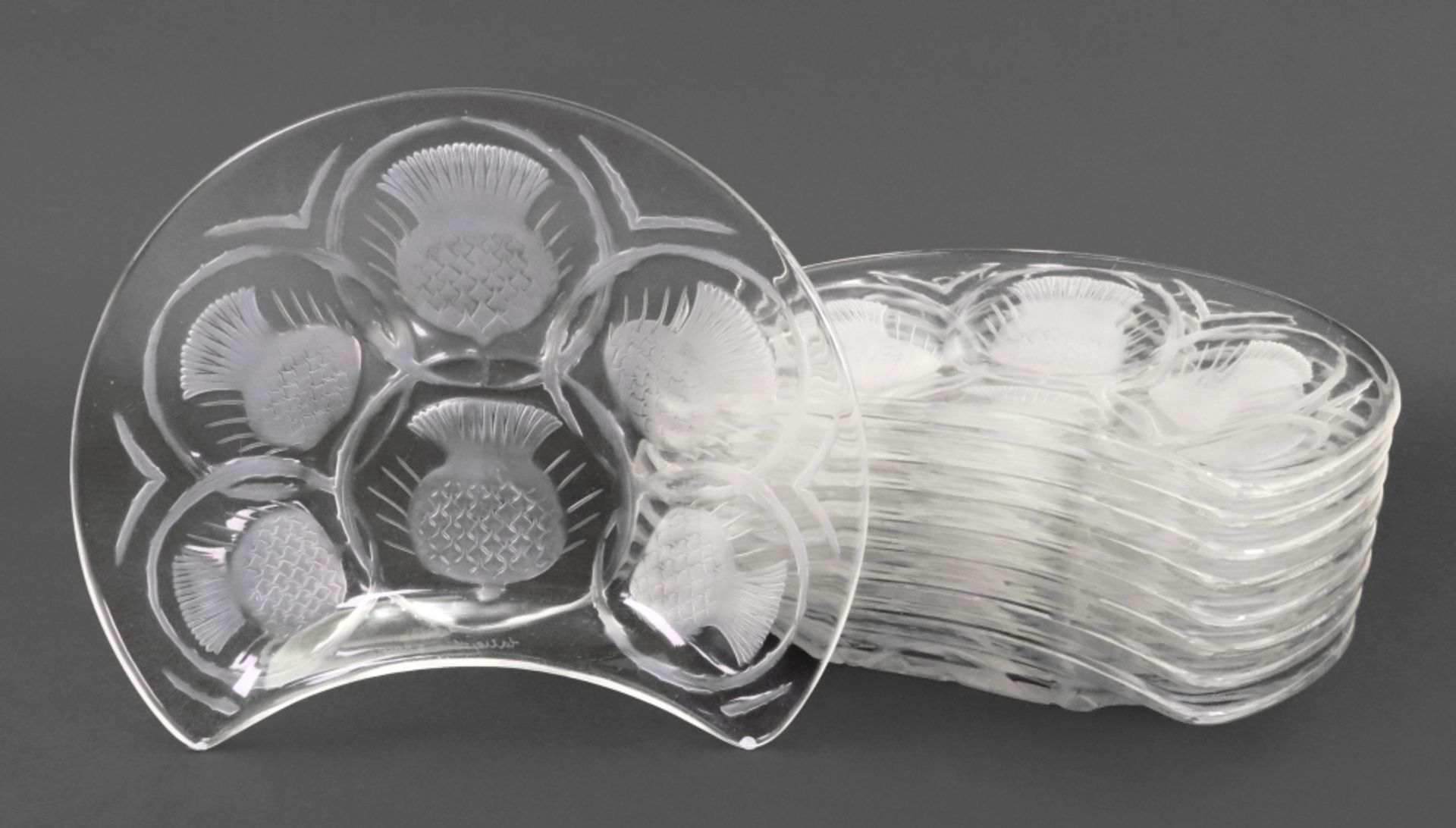 Lalique; a set of nine glass kidney shape salad plates, decorated with thistles,