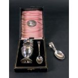 A cased silver egg cup, spoon and napkin ring,
