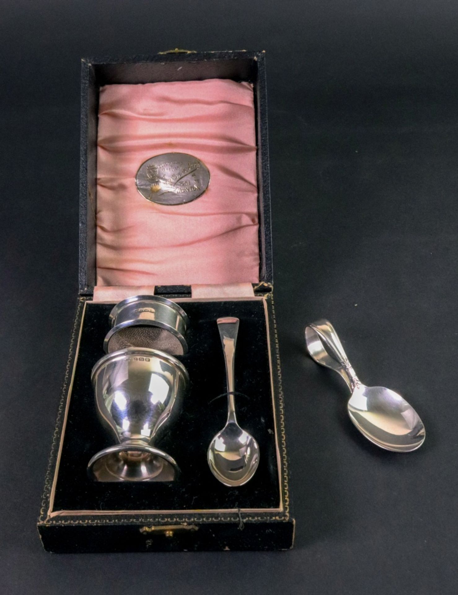 A cased silver egg cup, spoon and napkin ring,