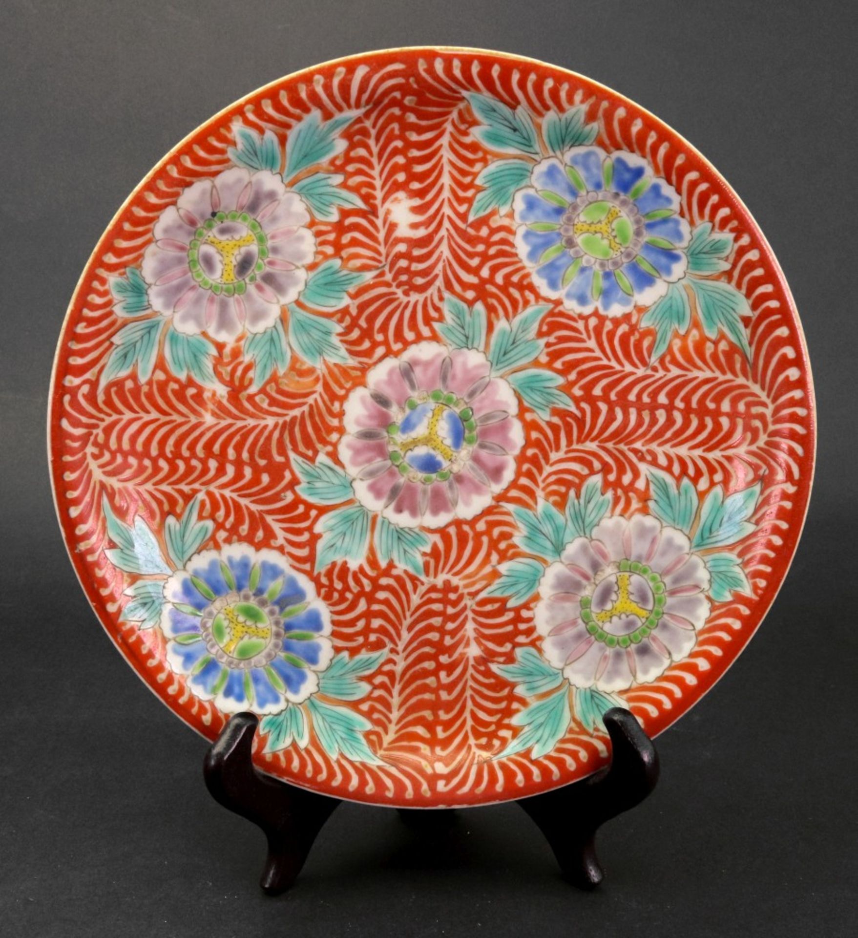A Japanese Imari plate, Meiji period, painted with five flowers against an iron red ground, - Image 2 of 2