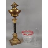 A late Victorian gilt metal oil lamp, with carved ebonised column,