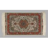A Ghom rug, with a central motif on a pale ground,