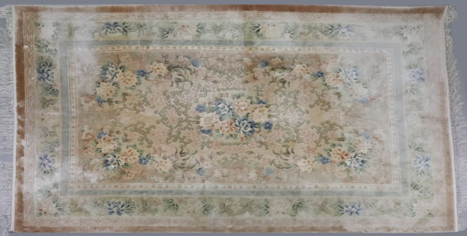 A modern silk rug, with a floral design within a border, on a cream ground, 246 x 169cm.
