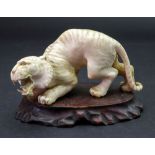 A Japanese ivory figure of a tiger, Meiji period, carved crouching with teeth bared, 11.
