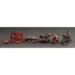 A group of six wooden netsuke to include; a figure riding a cow crossing a bridge, a reading lesson,