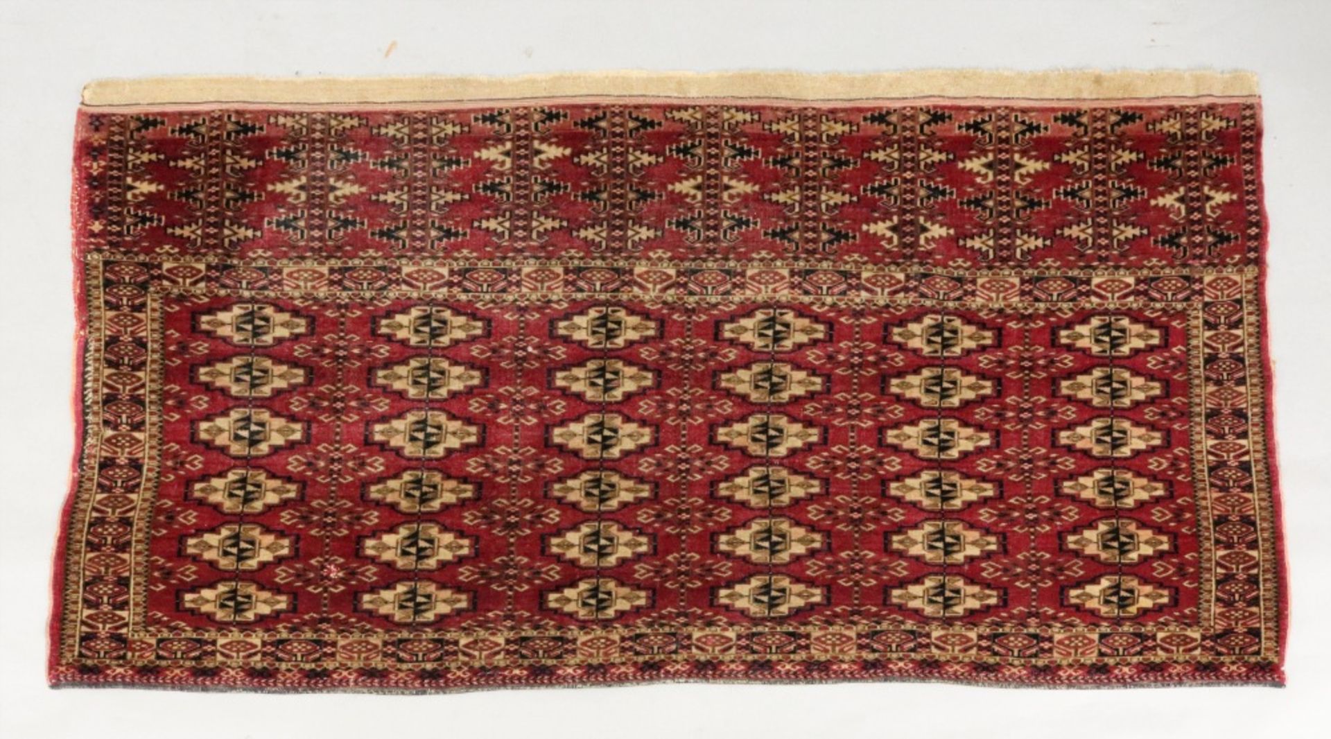 A Yomut Juval rug, with six rows of guls, on a crimson ground, 133 x 67cm.