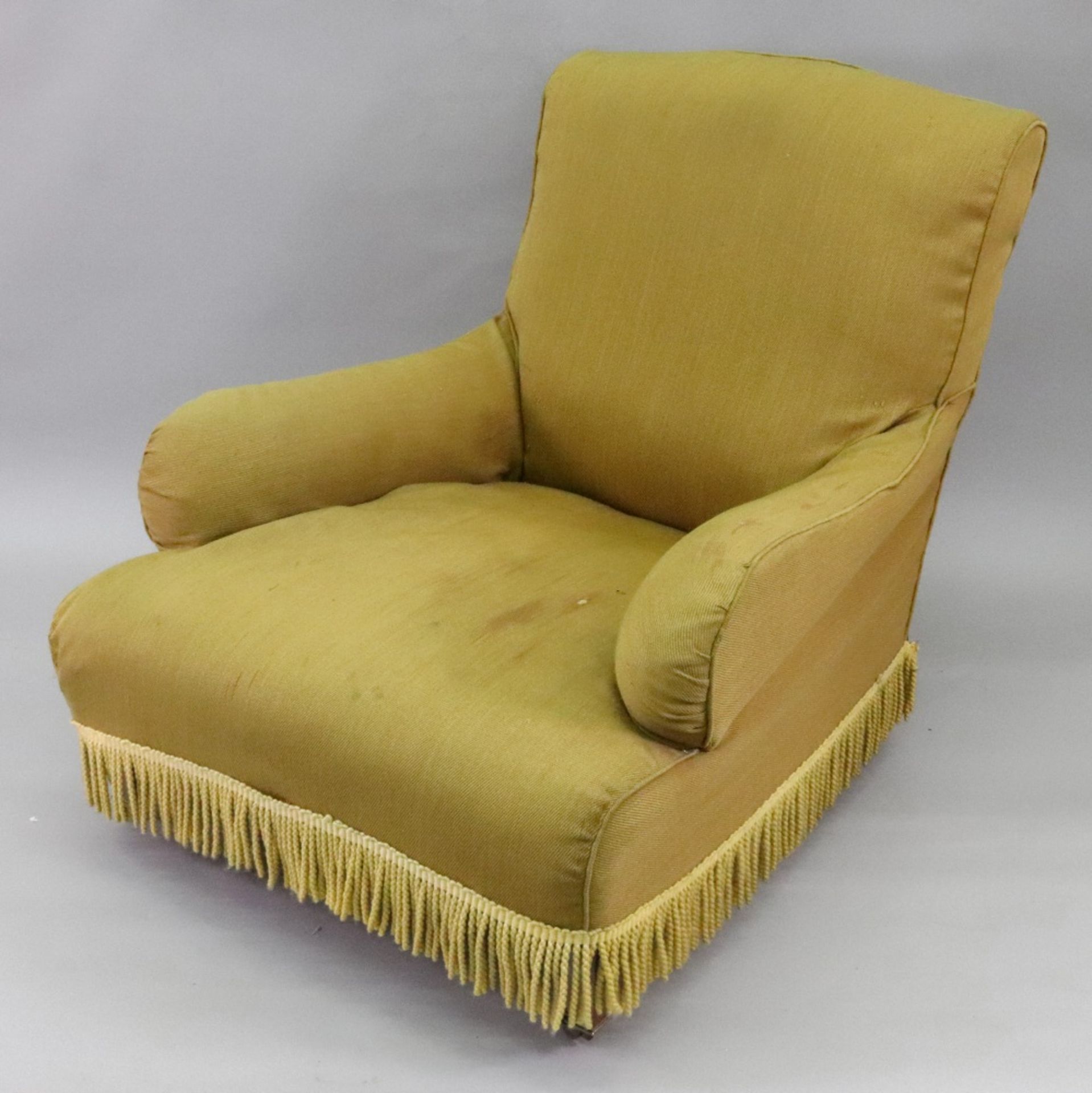 Howard & Sons; an upholstered deep seated armchair, on square tapered legs and brass castors,