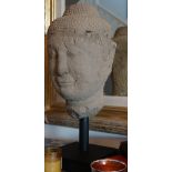 A Thai stone head on ebonised base, 61cm high, restorations.