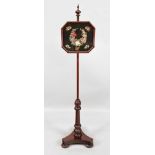 An early Victorian mahogany pole screen, with an octagonal glazed Berlin needlework banner,