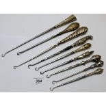 A collection of eight silver handled button hooks,