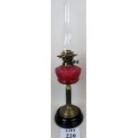 An old brass oil lamp & chimney with cranberry glass well est: £30-£40