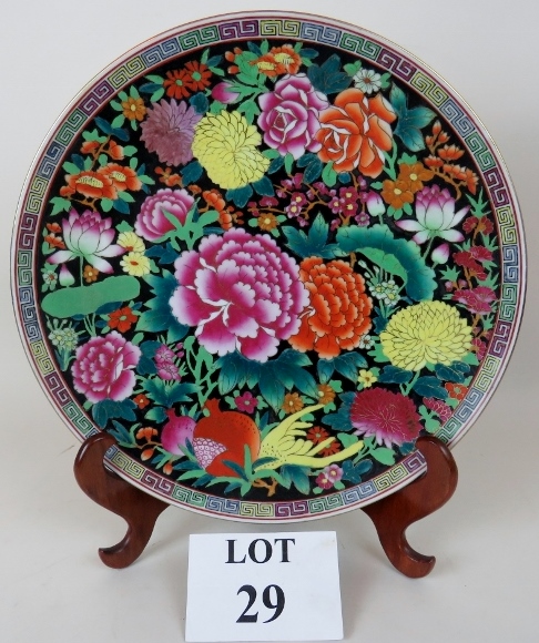 A modern Chinese porcelain charger elaborately painted in coloured enamels and gilt on a black