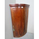 A 19th century bow front corner cupboard with a single door,