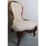 A Victorian carved mahogany framed ladies armchair upholstered in cream material,