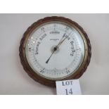 A wall hanging aneroid barometer dating from the early 1900's with a carved oak surround,