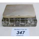 A glass stamp box with silver lid,