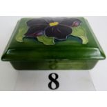 A Moorcroft box and cover, tube-lined with a flower and foliage on a green ground, impressed mark,