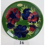 A Moorcroft cabinet plate, tube-lined with flowers and foliage on a green ground,