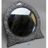 A silver framed circular mirror embossed with birds, flowers & scrolls,