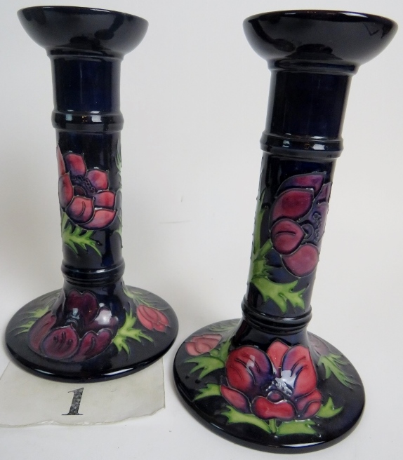 A pair of contemporary Moorcroft candlesticks, tube-lined with flowers and foliage on blue grounds,