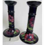 A pair of contemporary Moorcroft candlesticks, tube-lined with flowers and foliage on blue grounds,