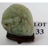 A Chinese carved jade scholar's rock, celadon on a fitted wooden stand,