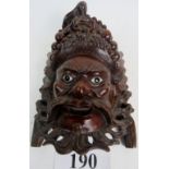 An Asian carved hardwood wall mask, well carved intricate detail throughout, inset with glass eyes,