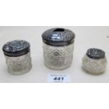Three cut glass jars with silver tops,