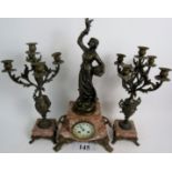 A French bronzed cast metal and veined rouge marble three piece clock garniture,