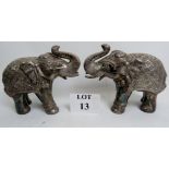 A pair of Asian silvered wooden models of elephants wearing decorative adornments, 22cm high,