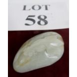 A pale celadon Jade carving of a fish on a rock with russet inclusions, 55mm long,