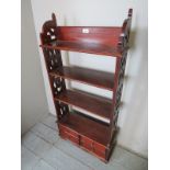 A Georgian style (Indonesian) mahogany open shelf unit with fretwork side panels over small drawers,