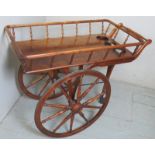 An early 20th century, possibly walnut, drinks trolley, with large wooden wheels, with rubber tips,