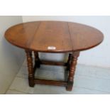 A late 20th century pale oak drop leaf occasional table with oval top,