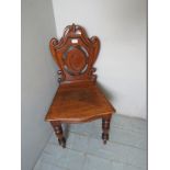 A c1900 pale oak hall chair with detailed carved back,