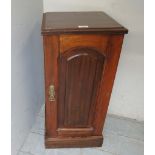 A late Victorian walnut bedside cupboard with an arched panelled door,