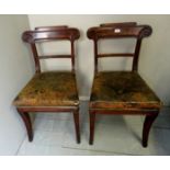 A pair of Regency mahogany framed chairs with worn green leather seats over reeded sabre legs,