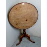 A Georgian pale mahogany tilt top table with a dished top over turned column and triple splayed