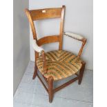 A late 19th century rustic chair with cream upholstered arms over a rush work two tone seat,