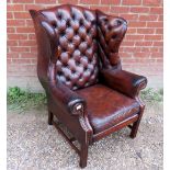 A 20th century brown leather deep buttoned winged armchair,