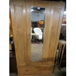 A late Victorian pine wardrobe with a central door with mirror over a deep drawer,