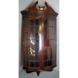 An early 20th century mahogany corner wall cabinet with glazed bow fronted doors beneath a blind