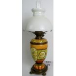 A Victorian oil lamp with brass base and the body in a yellow ground with floral decoration,