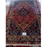 A 20th century Persian wool rug with central diamond on blue/claret field, 200cm x 126cm approx,